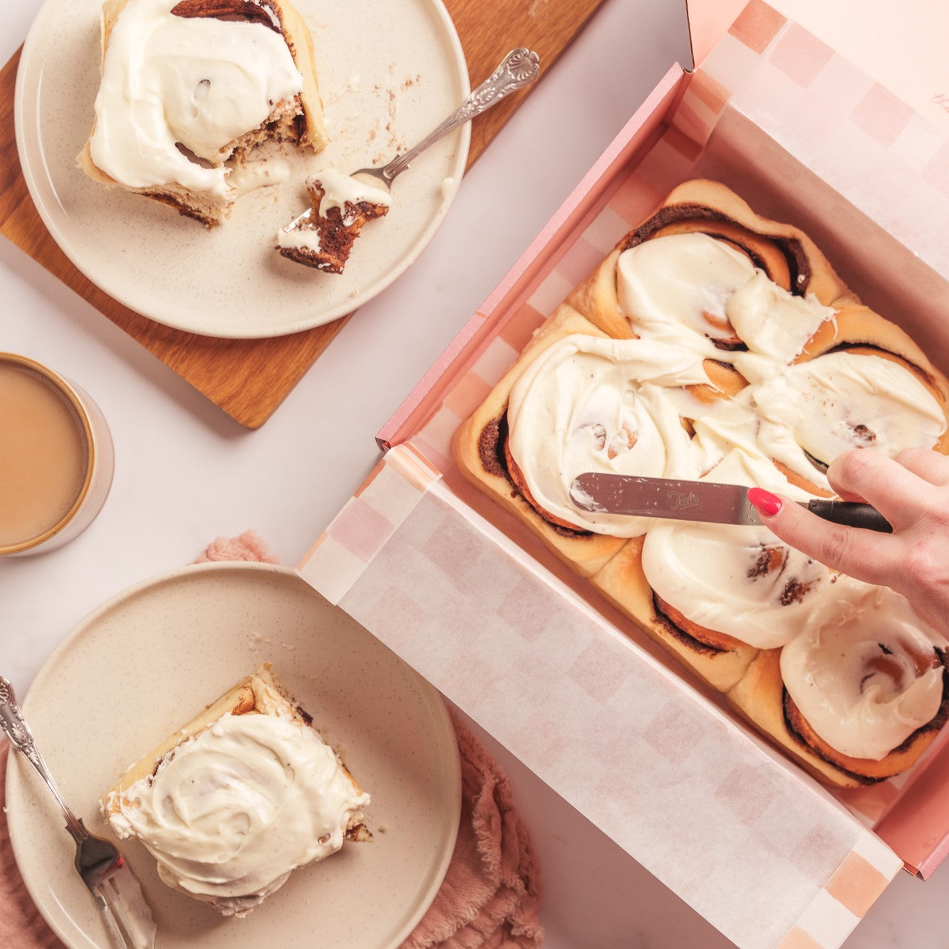 Cinnamon Buns in a box being frosted