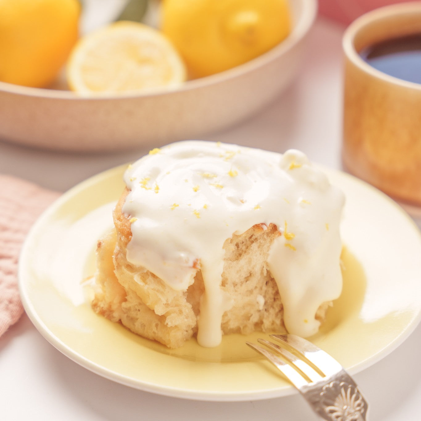 Lemon Drizzle bun on a yellow plate with a fork