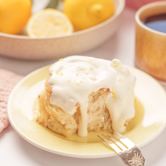 Lemon Drizzle bun on a yellow plate with a fork